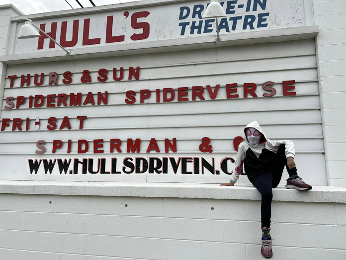 My daughter Rose in her Spider-Gwen hoddie and mask at one of the many screenings of "Spider-Man: Across the Spider-Verse" we went to in 2023, this one at our local drive-in.